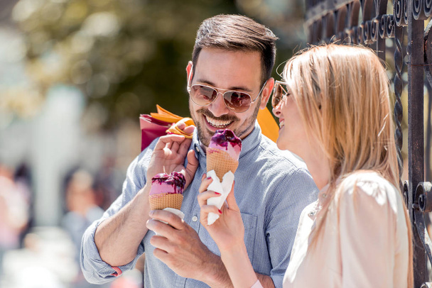 陽気な若いカップルがアイスクリームを食べるします。市内でアイスクリームを食べて素敵なカップルの画像. - 写真・画像