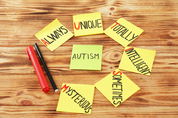 Pegatinas con abreviatura expansión de la palabra "autismo" sobre fondo de madera
 - Foto, Imagen