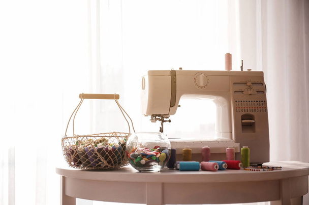 Modern sewing machine with threads on table - Photo, Image