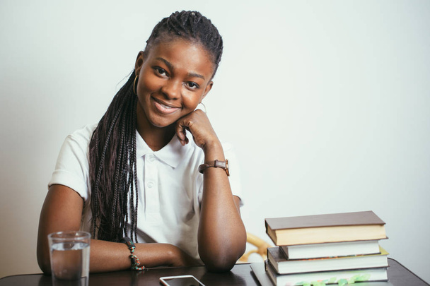 african young woman sitting at table with books at home - Photo, image