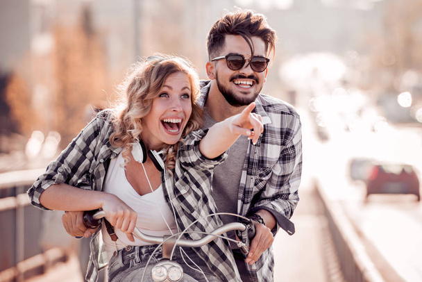 Couple heureux faisant du vélo en ville, souriant et s'amusant en été coloré en ville
. - Photo, image