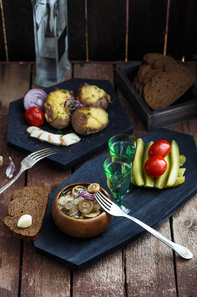 Vodka with pickled mushrooms on the Board. On wooden background. - Photo, Image