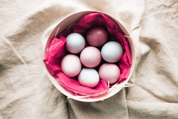  painted Easter eggs in box with pink paper, sackcloth background, rustic festive composition - Foto, Imagem