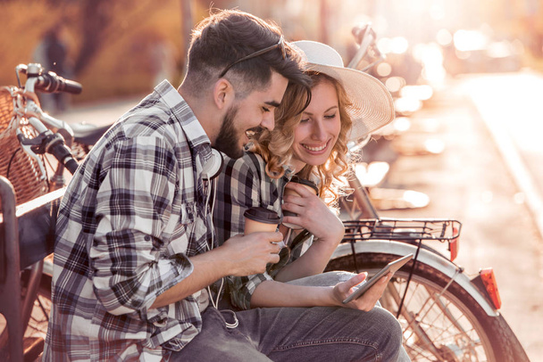 Mladí milující pár sedí na lavičce v parku a Bavíte se s tabletem. Láskou a něhou, stylu života. - Fotografie, Obrázek