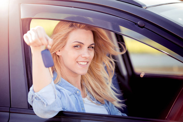 Ευτυχής όμορφη νεαρή γυναίκα που κάθεται σε ένα αυτοκίνητο στην όμορφη ηλιόλουστη μέρα του καλοκαιριού.  - Φωτογραφία, εικόνα