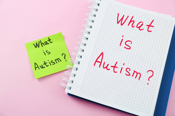 Notepad and sticker with text WHAT IS AUTISM? on color background - Foto, Bild