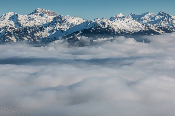 Nieve en la cima de las montañas y niebla en el valle
 - Foto, imagen