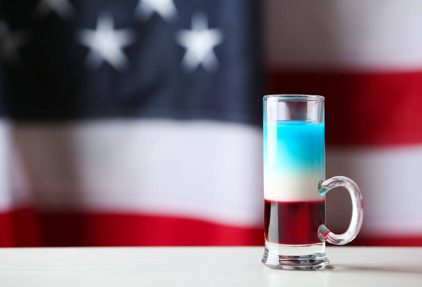 Layered cocktail in colors of American flag on table against blurred background - Fotografie, Obrázek