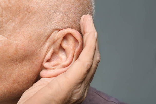 Elderly man with hearing problem on grey background, closeup - Φωτογραφία, εικόνα