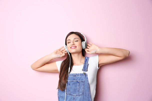 Woman listening to audiobook through headphones on color background - Foto, Imagem