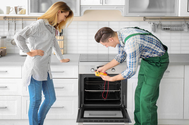 Housewife with worker near oven in kitchen - Foto, imagen