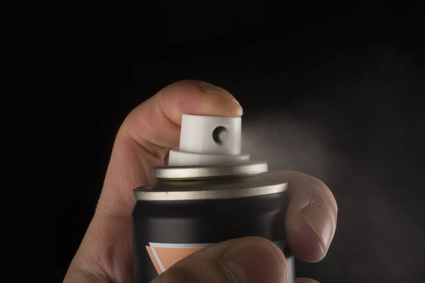 Vista de perto da mão humana e frasco de spray isolado em preto
 - Foto, Imagem