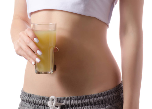 Beautiful young woman holding belly glass of juice healthy vitamin - 写真・画像