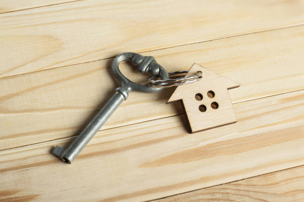 Pojęcie nieruchomości lub nieruchomości na wynajem. Symbolem domu z kluczem i monety na podłoże drewniane. - Zdjęcie, obraz
