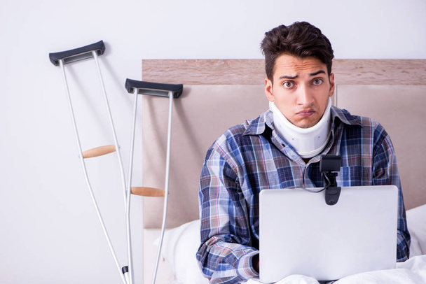 Hombre lesionado charlando en línea a través de la webcam en la cama en casa - Foto, imagen