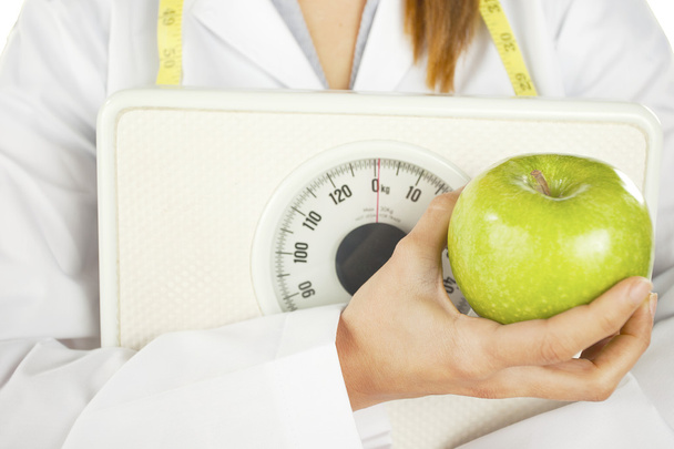 Nutritionist holding a green apple and weight scale - Fotó, kép