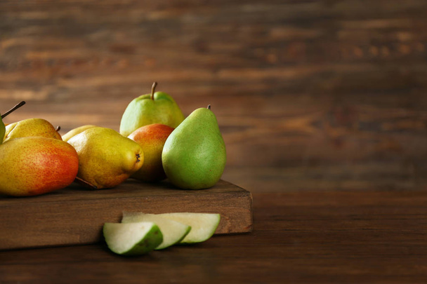 Board with delicious ripe pears on wooden table - Fotografie, Obrázek