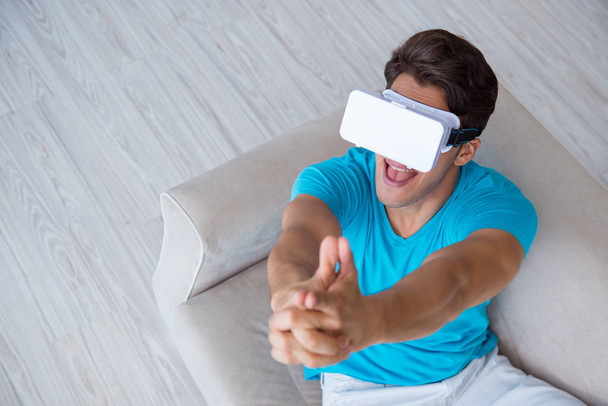 Young man wearing VR glasses relaxing on couch sofa - Fotografie, Obrázek
