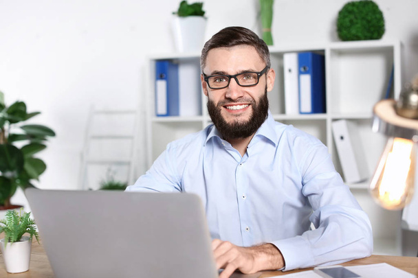 Portrait of handsome bearded man with laptop indoors - 写真・画像