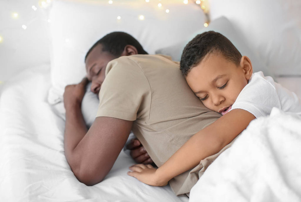 African American man die met zijn zoon in bed slapen. Familie bedtijd - Foto, afbeelding