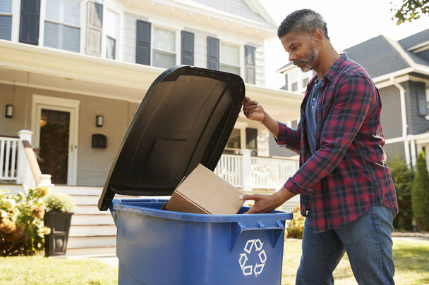 Man Filling Recycling Bin On Suburban Street - 写真・画像
