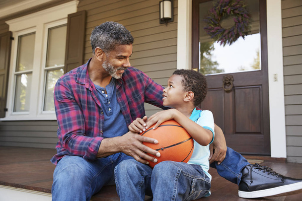 Father And Son Discussing Basketball On Porch Of Home - Foto, Imagen