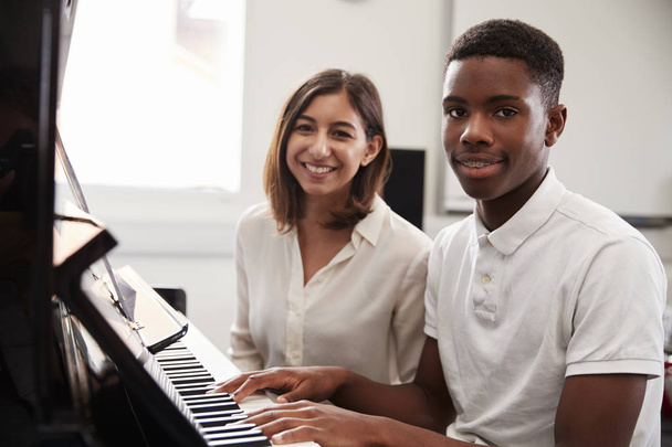 Portrait Of Pupil With Teacher Playing Piano In Music Lesson - Photo, image