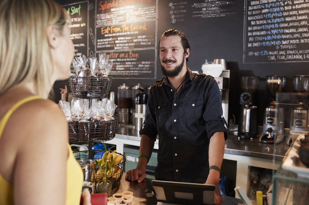 Camarero tomando pedido de cliente femenino en cafetería
 - Foto, Imagen