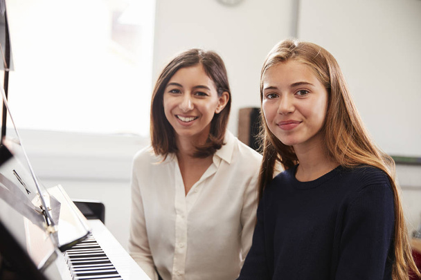 Portrait Of Pupil With Teacher Playing Piano In Music Lesson - Foto, imagen