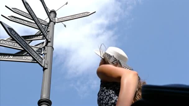 Nízké pohled na znamení s evropskými městy, mladá žena, při pohledu na ně - Záběry, video