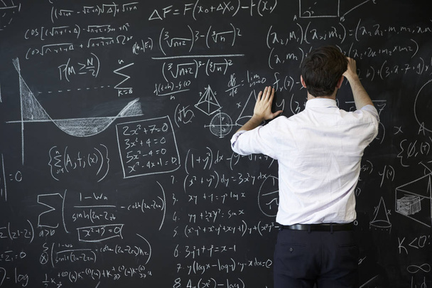 Young man writing on blackboard - Photo, image