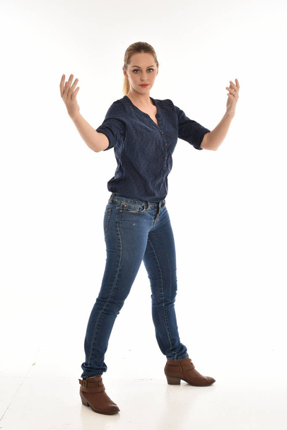 Pełna długość Portret dziewczyny sobie proste niebieska koszula i jeansy, stałego pose.isolated na tle białego studia. - Zdjęcie, obraz