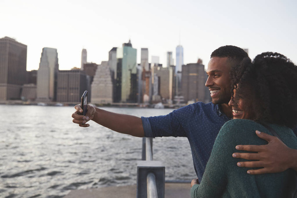 Young black couple taking photo on quayside, side view - Foto, Imagem