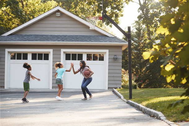 Mother And Children Playing Basketball On Driveway At Home - Foto, imagen