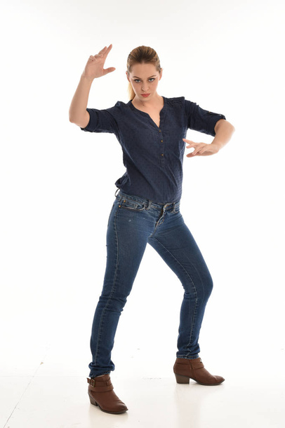 retrato de longitud completa de la muchacha que usa camisa azul simple y pantalones vaqueros, de pie pose.isolated sobre fondo de estudio blanco
. - Foto, Imagen