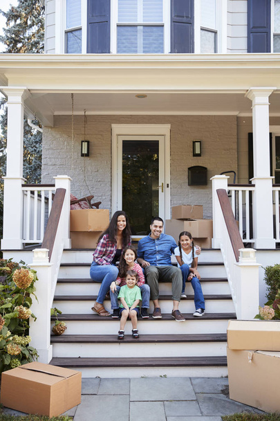 Family Sitting On Steps Of New Home On Moving In Day - Foto, Imagen