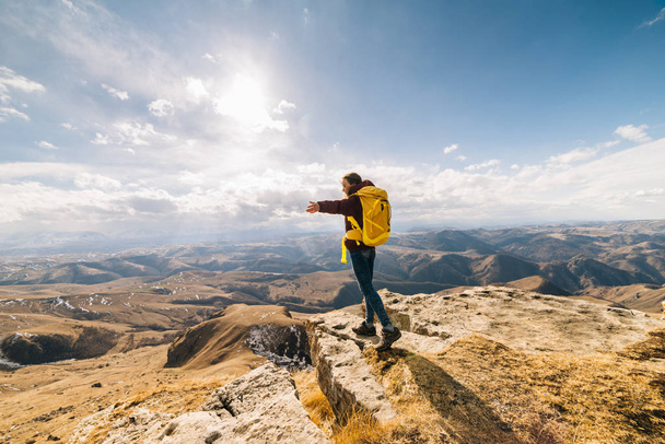 woman tourist is standing with a backpack on the background of high mountains on a sunny day - Foto, immagini