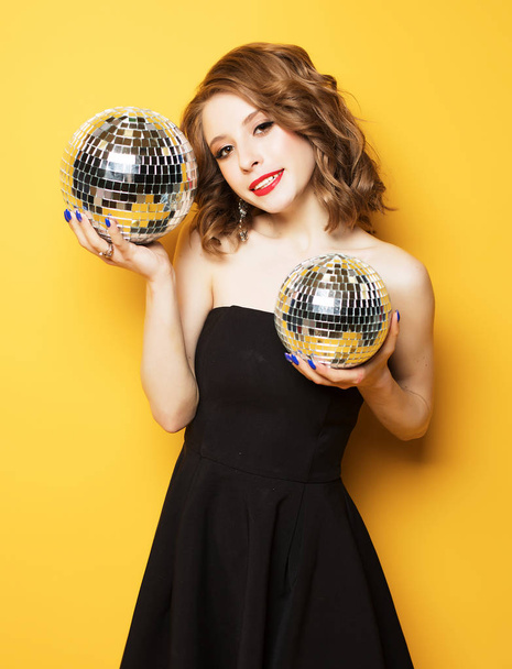 Beautiful young sensual woman wearing black dress and holding disco ball - Foto, imagen