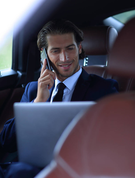 Komea liikemies käyttää matkapuhelinta autossa
. - Valokuva, kuva