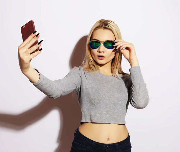 Pretty hipster girl making selfie over white background. - Valokuva, kuva