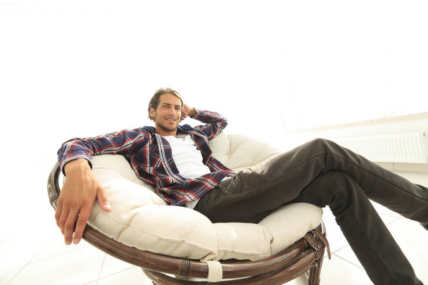 serious guy rests sitting in a large comfortable chair. side view. - Photo, image
