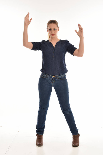 портрет дівчини в простій блакитній сорочці та джинсах, стояча поза. ізольовано на білому студійному фоні
. - Фото, зображення