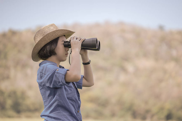 Mujer usar sombrero y mantener binocular en el campo de hierba
 - Foto, imagen
