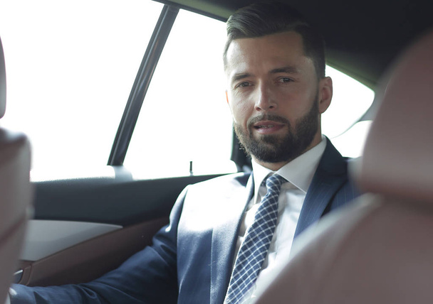 handsome bearded businessman sitting on back seat of car - Fotografie, Obrázek
