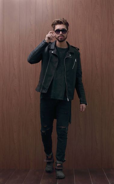 a man is standing in a black leather jacket and jeans - Fotografie, Obrázek