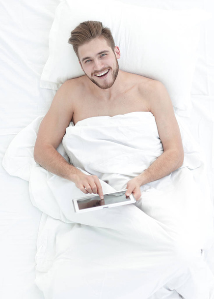 background image of man with digital tablet in the bedroom - Photo, Image