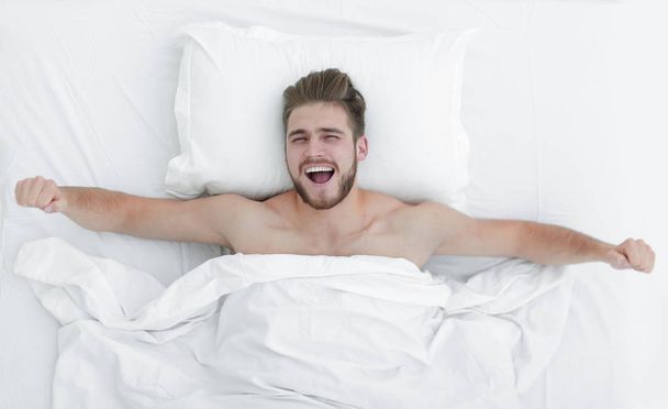 top view. happy man waking up in a comfortable bed - Fotoğraf, Görsel