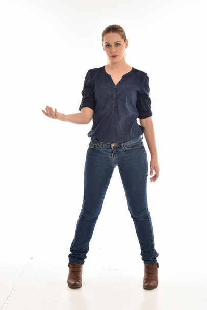 ホワイト スタジオの背景に pose.isolated に立っているシンプルなブルーのシャツとジーンズを身に着けている女の子の完全な長さの肖像画. - 写真・画像