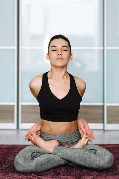 Bella ragazza bruna seduta in posa di loto. Il modello pratica yoga in una stanza luminosa
. - Foto, immagini