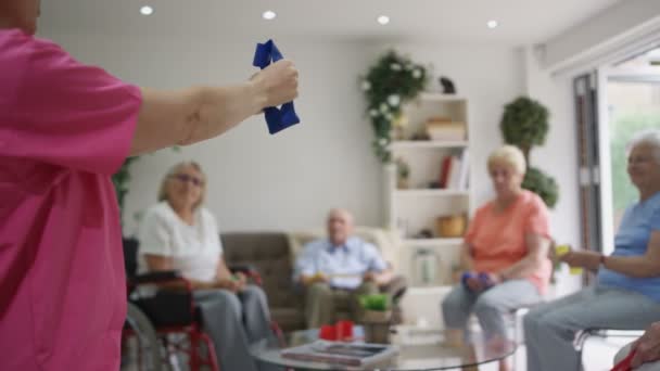 Enfermera joven mostrando grupo de ancianos algunos ejercicios con una banda de resistencia en el hogar de ancianos
. - Imágenes, Vídeo